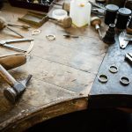 Working desk for craft jewelery making with professional tools. Grunge wooden table. View from above. Copy space.